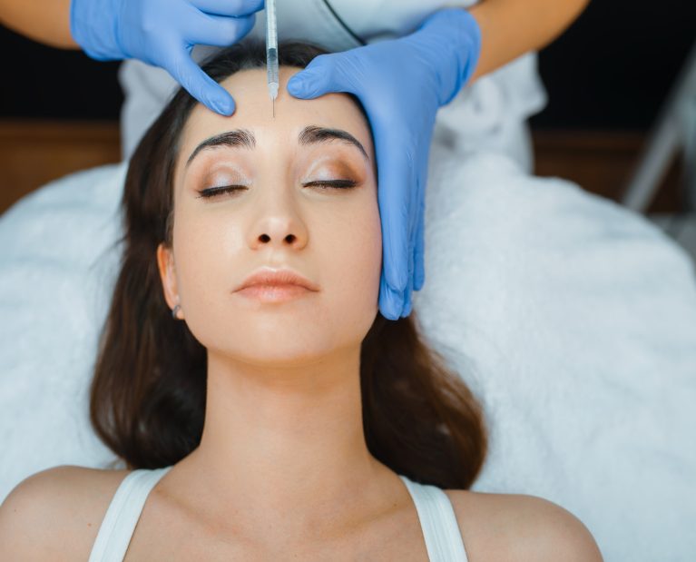Cosmetician gives face botox injections to patient