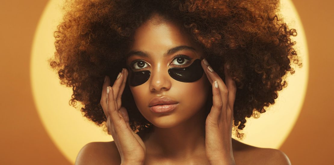 Young beautiful african woman standing, wearing eye patches against dark circles